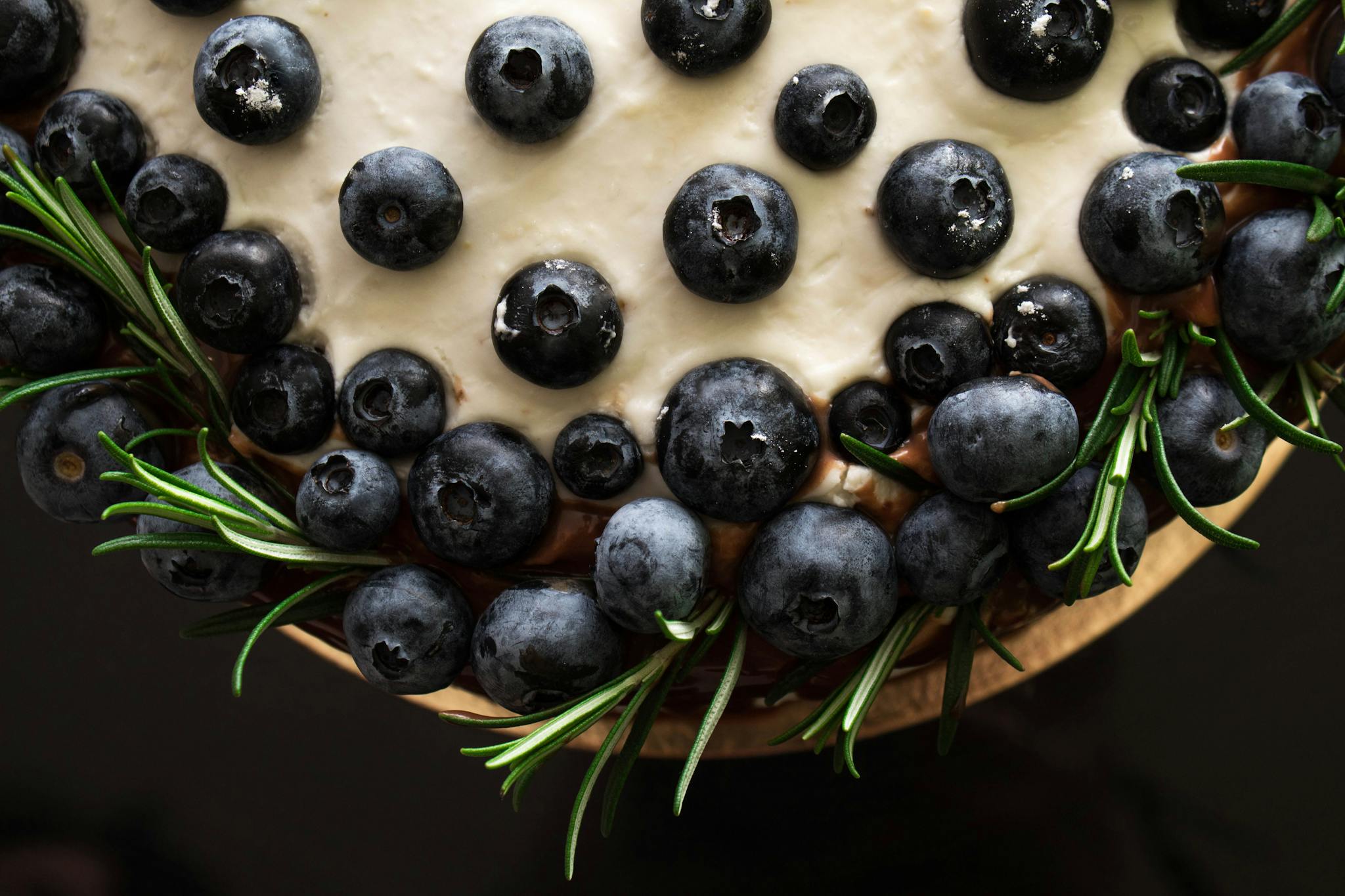 Close-up of a blueberry cake adorned with fresh rosemary, ideal for food enthusiasts.