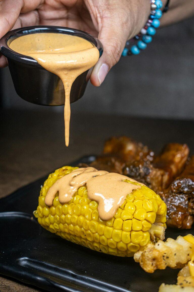 Close-up of corn on the cob drizzled with chipotle sauce, perfect for a flavorful meal.